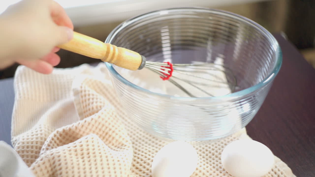 Food cooking equipment. Whisk in glas bowl. Closeup. Ingredients for cake baking