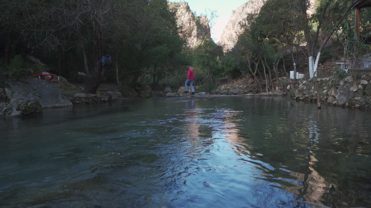 mujer feliz cruzando el río durante un viaje de vacaciones en la montaña atlas en marruecos