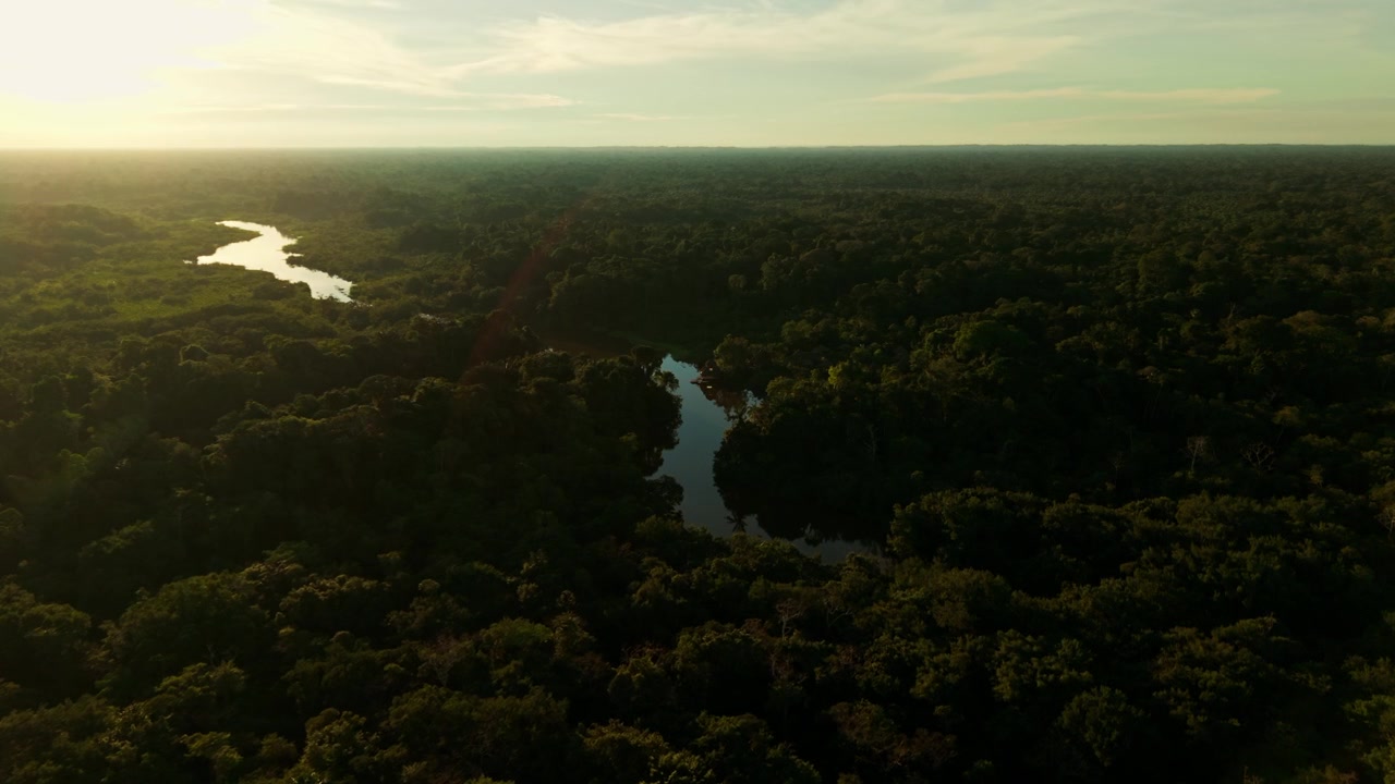 Majestætisk luftfoto af en snoet flod i den frodige Amazonas regnskov under en gylden solnedgang.