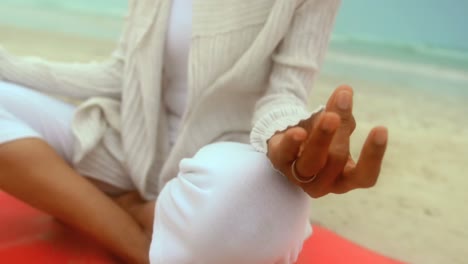 Close-up-of-active-senior-African-American-woman-doing-yoga-on-exercise-mat-at-the-beach-4k