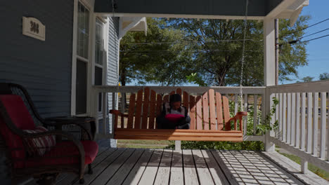 a serene and picturesque stock footage clip showcasing a smooth camera motion ascending the stairs of a front porch, leading to a charming scene of a little girl engrossed in a tablet