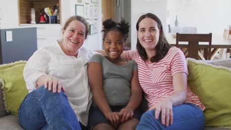 Retrato-De-Una-Feliz-Pareja-De-Lesbianas-Caucásicas-Y-Su-Hija-Afroamericana-Abrazándose-Y-Sonriendo