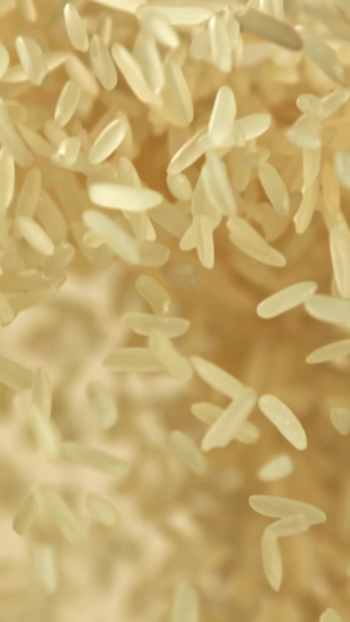Chicchi di riso a grano lungo crudo che cadono al rallentatore