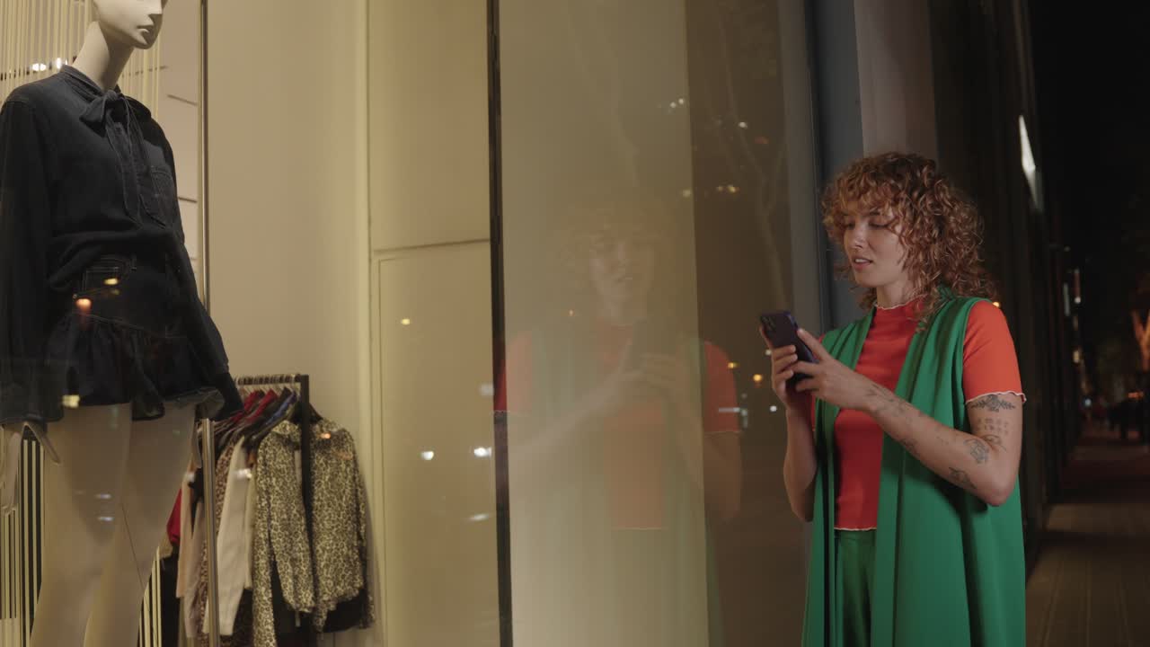 Woman Using Smartphone Near Store Window at Night
