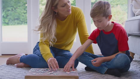 mother and son at home doing jigsaw puzzle on floor of lounge together