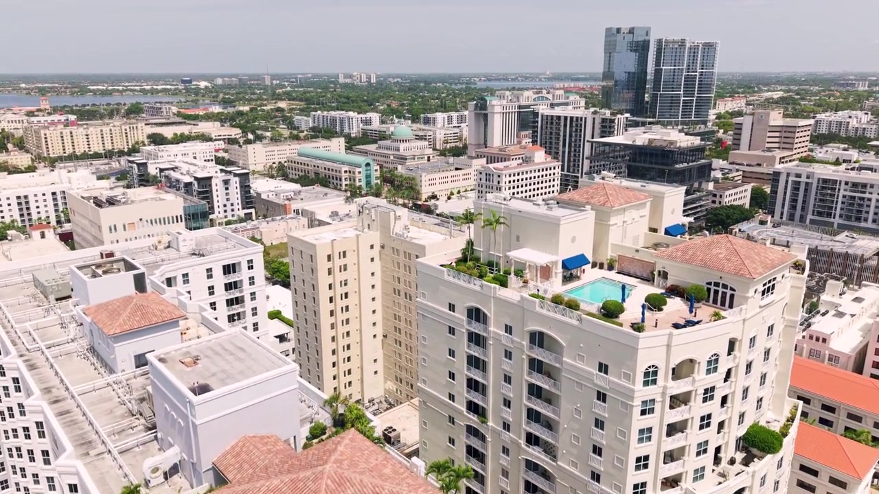 Aéreo: tomada de drone de estabelecimento dos arranha-céus do centro de West Palm Beach com palmeiras durante o dia na Flórida, EUA