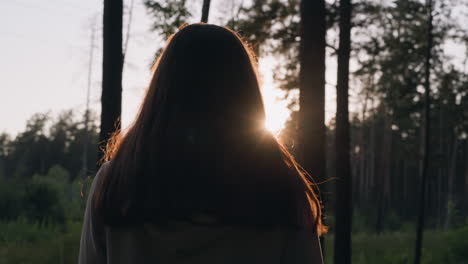 woman walks in forest in evening. young lady with long loose hair copes with emotional distress by walking in fresh air. solitude with nature to calm down