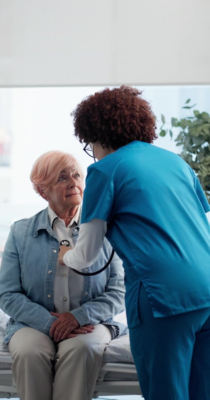 Nurse Examining Senior Patient with Stethoscope in Hospital Room