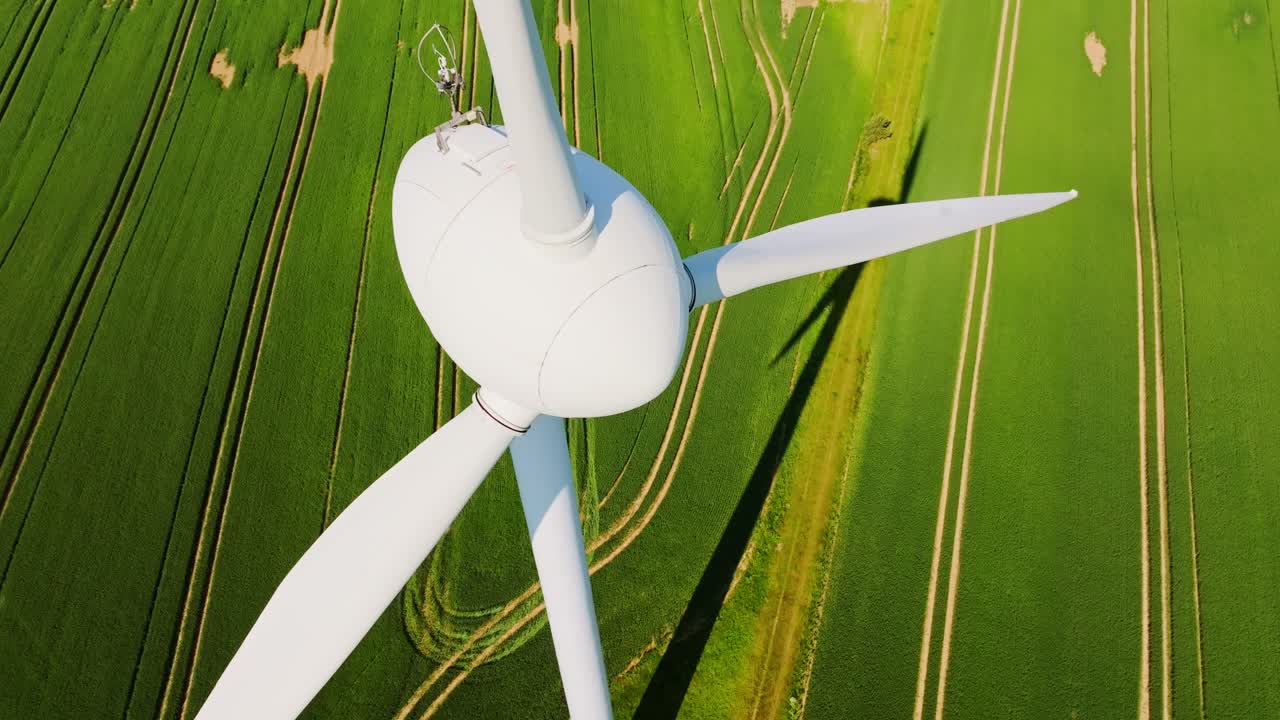 Frozen wind turbine above Latvian fields on sunny summer day aerial diving view