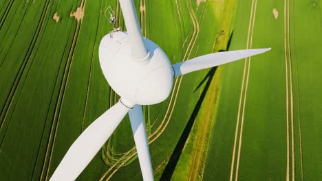 frozen wind turbine above latvian fields on sunny summer day aerial diving view