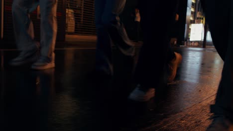 people walking on a wet city street at night
