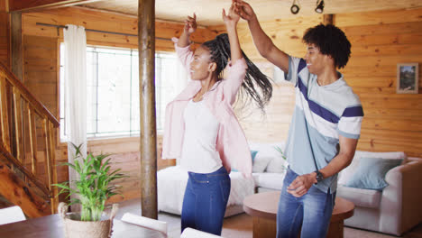 happy african american couple dancing together in log cabin, slow motion