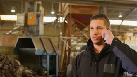 worker talking on mobile phone in foundry workshop 4k