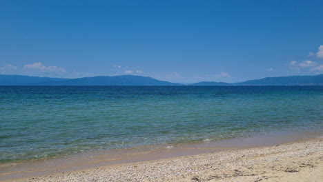 平靜的海浪和晴朗的藍天 在一個夏天的陽光明<unk>的希臘海灘上