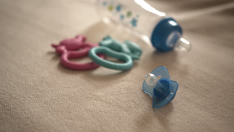 close up pan of a pacifier, baby bottle, and teething toys