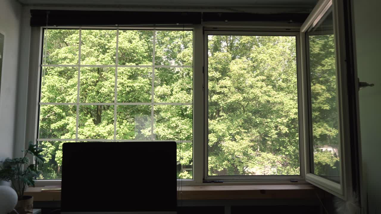 Guy closing the window and blinds of his home office