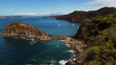 Drohne-Fliegt-über-Die-Felsige-Bucht-Von-Guanacaste-Mit-Im-Hintergrund-Festgemachten-Segelbooten