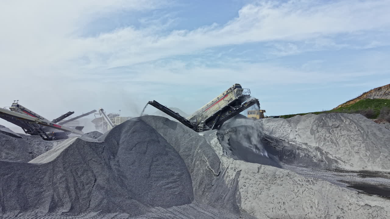 Granite quarry activity with machinery processing rock and high piles of stone on a cloudy day