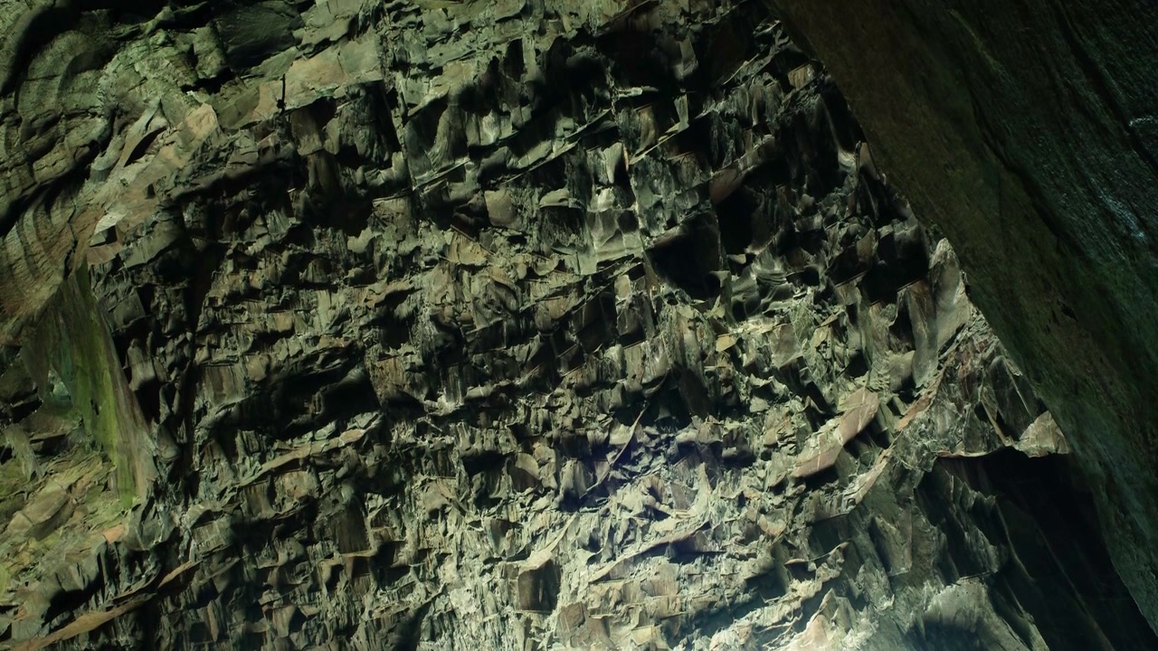 Slow moving shot of the rugged ceiling inside Cathedral Cavern in Little Langdale, highlighting dramatic rock formations, geological textures, and the vast scale of the historic underground chamber
