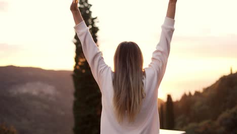 happy young blonde woman enjoying mountain view, back view