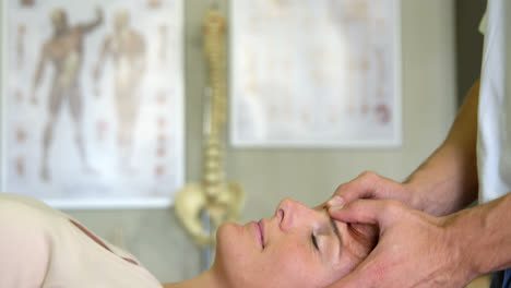 fisioterapeuta dando masaje de cabeza a una paciente femenina