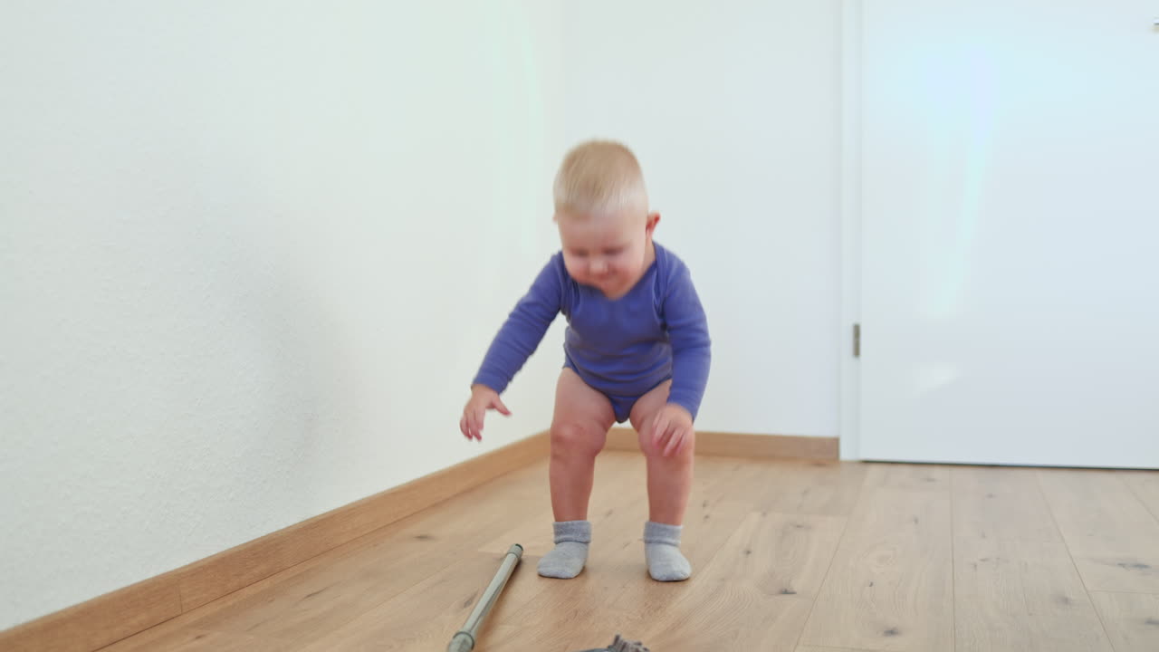Un bambino piccolo lava il pavimento con un mop. Il bambino aiuta a pulire il pavimento. Un bambino in un body di cotone