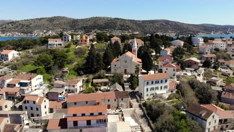 a drone shot of a church in rogoznica, croatia, and the rest of the town