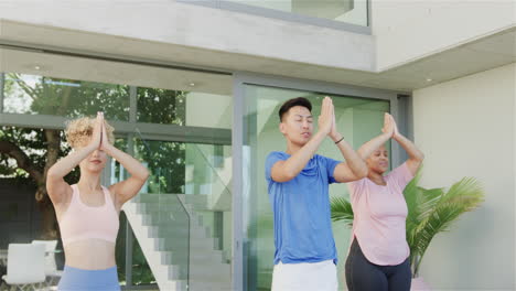 young asian man and biracial women practice yoga outdoors