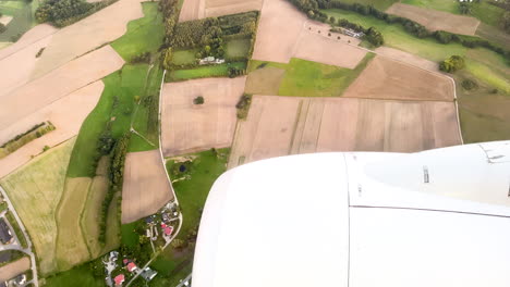 campos de campo, casas de la ciudad, y motor a reacción visto a través de la ventana del avión