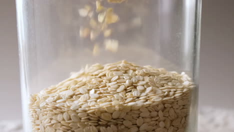sesame seeds falling into glass jar