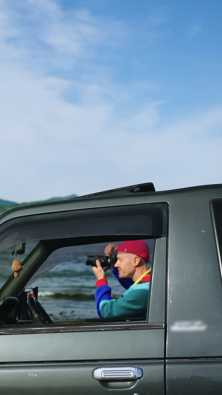 Uomo che fotografa un paesaggio costiero panoramico dall'auto