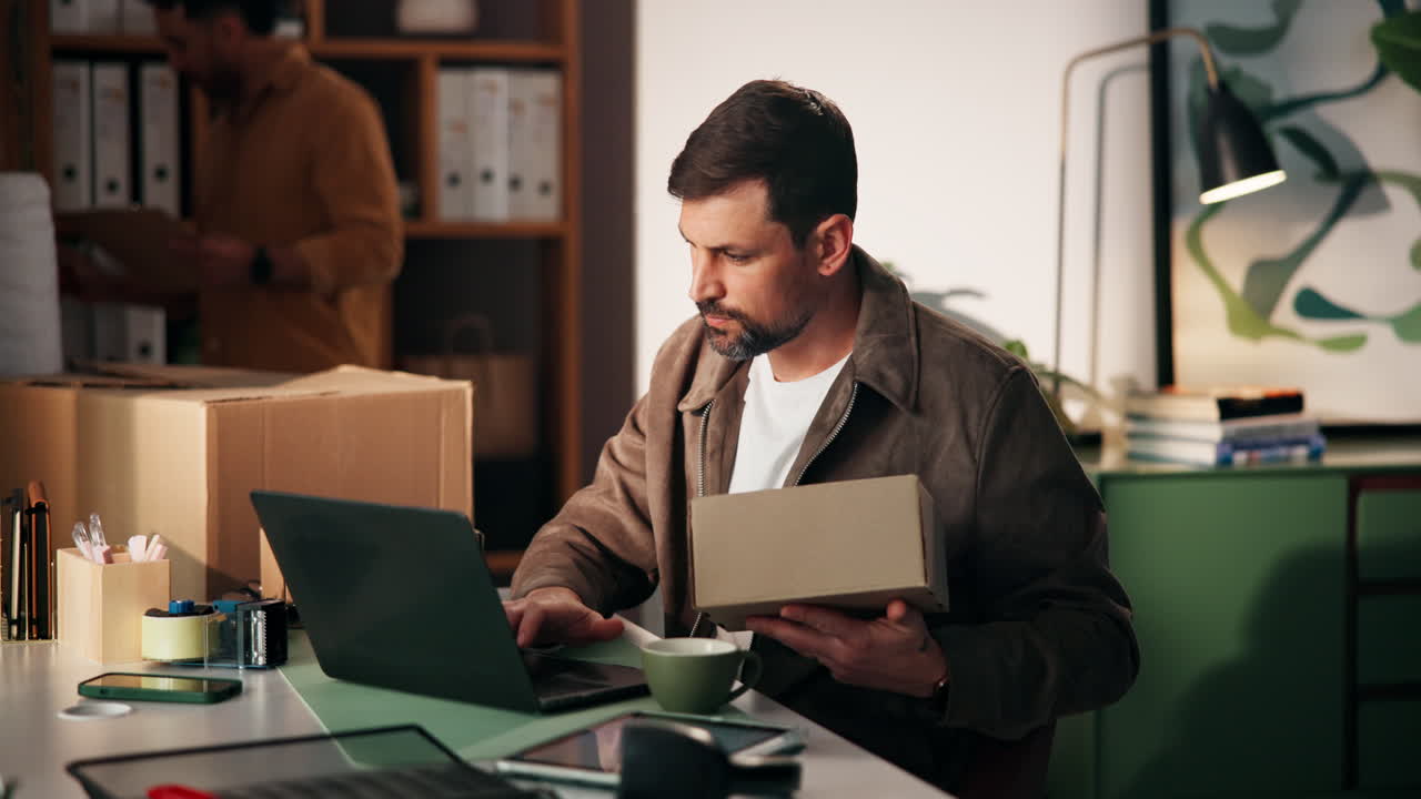 Man working on laptop with box in office