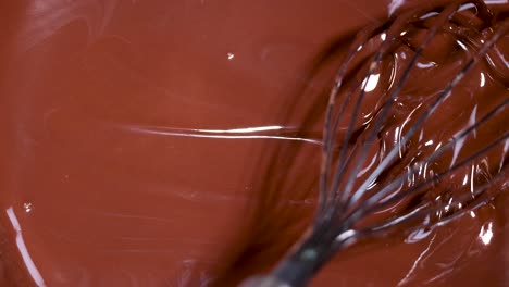 a whisk stirring rich, melted chocolate