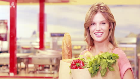 Young-happy-woman-smiling-at-camera-with-bought-goods