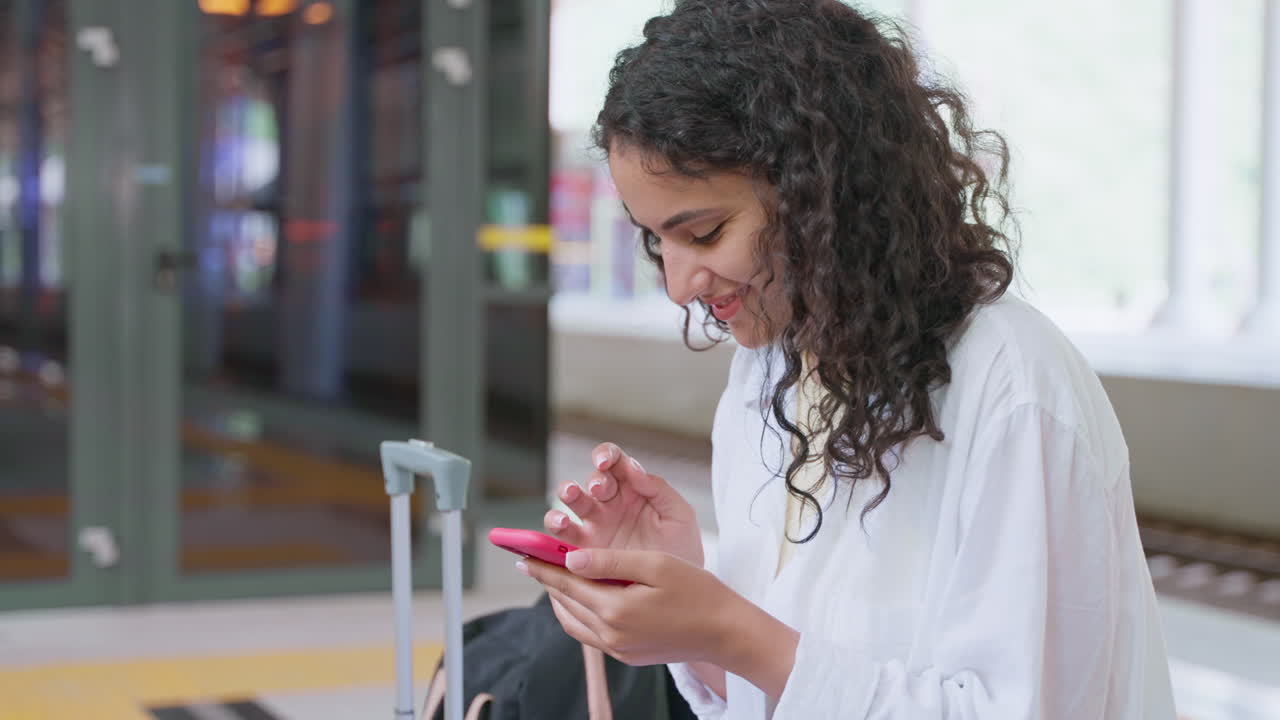 mujer usando el teléfono en una estación de tren