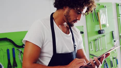 Mechanic-using-digital-tablet-in-workshop