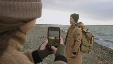 vista trasera de una adolescente sosteniendo un teléfono inteligente