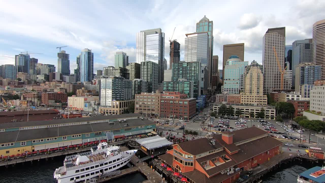 Mesmerizing drone flight over Seattle's bustling waterfront district, showcasing the vibrant blend of business activity, waterfront piers, towering skyscrapers, and architectural marvels