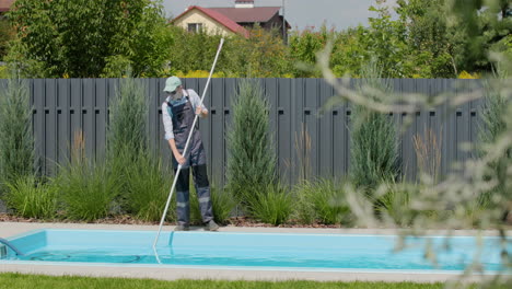 a worker cleans a swimming pool with a special vacuum cleaner.