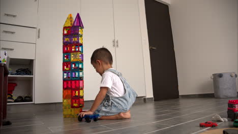 Cámara-Lenta-De-Un-Travieso-Niño-Hispano-Latino-Destruyendo-Una-Torre-Hecha-De-Azulejos-Magnéticos-Con-Autos-De-Juguete-Dentro