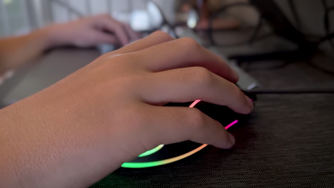 primer plano de la mano de un niño usando un mouse y teclado de computadora para juegos