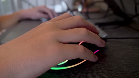 closeup of a young kid hand using a gaming computer mouse and keyboard