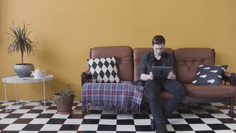 man using tablet on a couch in a living room