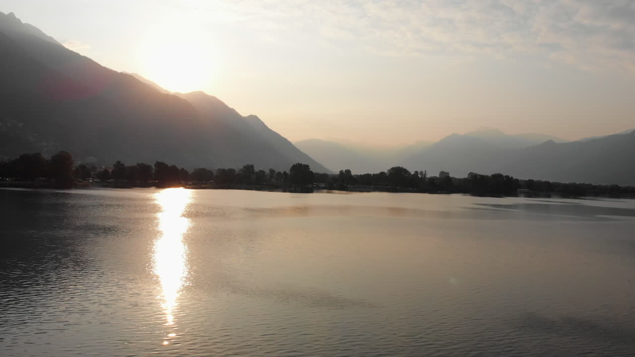 Płynne panoramowanie brzegu jeziora Maggiore o wschodzie słońca, z górami w tle, Locarno, Szwajcaria.
