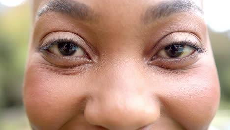 Retrato-De-Cerca-De-Los-Ojos-De-Una-Feliz-Mujer-Afroamericana-Sonriendo-En-El-Jardín,-En-Cámara-Lenta