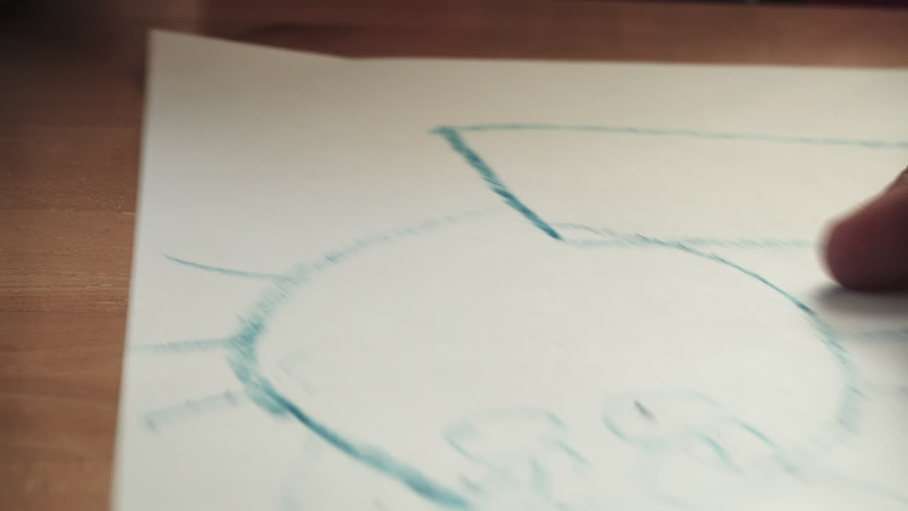 un niño dibuja un gato azul con un crayón mientras la cámara se desplaza hacia la izquierda