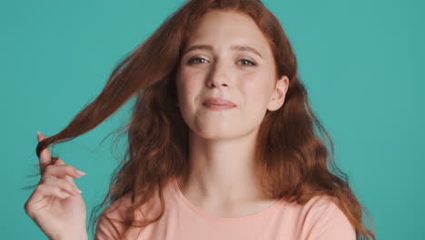 Redheaded-girl-in-front-of-camera-on-turquoise-background.