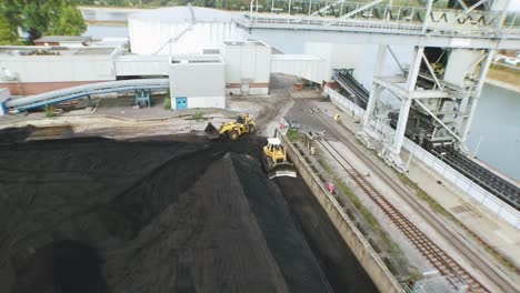 Drone-flight-over-a-big-coal-field-at-a-european-power-plant-with-crane-structures-coming-into-view