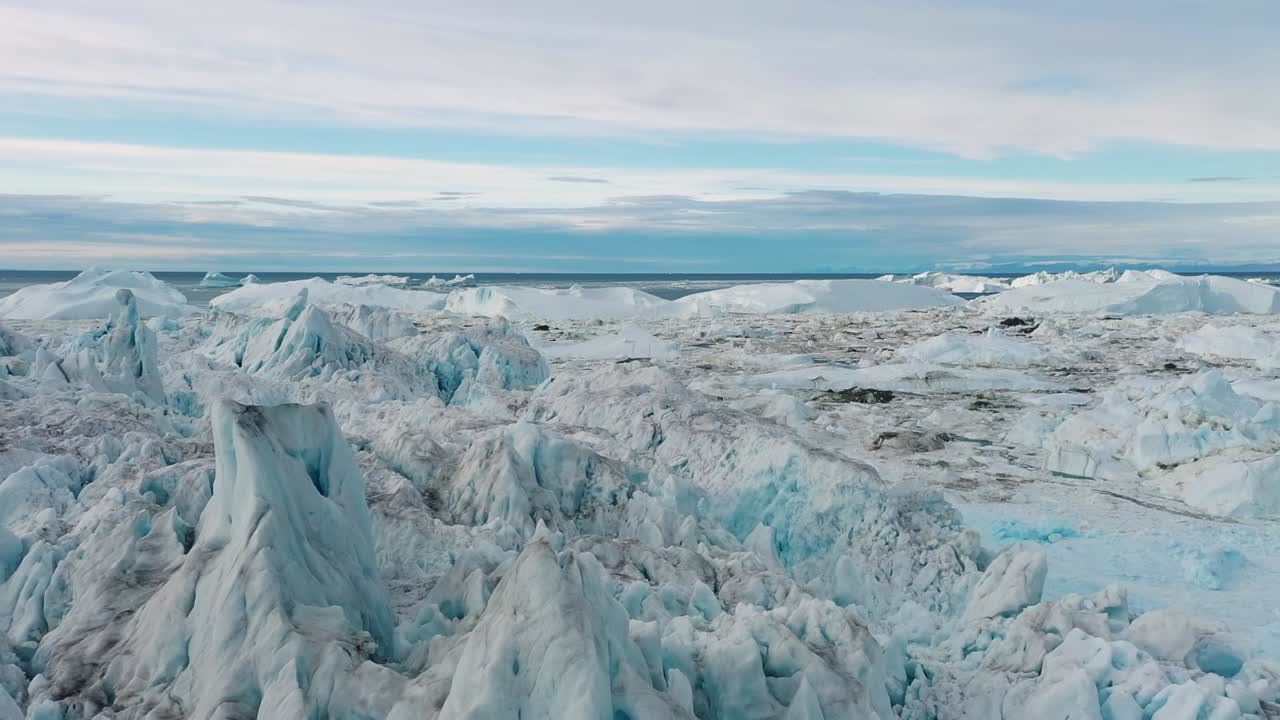 Drone view of an immense glacier field in Greenland with rugged formations and blue tones, capturing the raw beauty and power of the Arctic wilderness