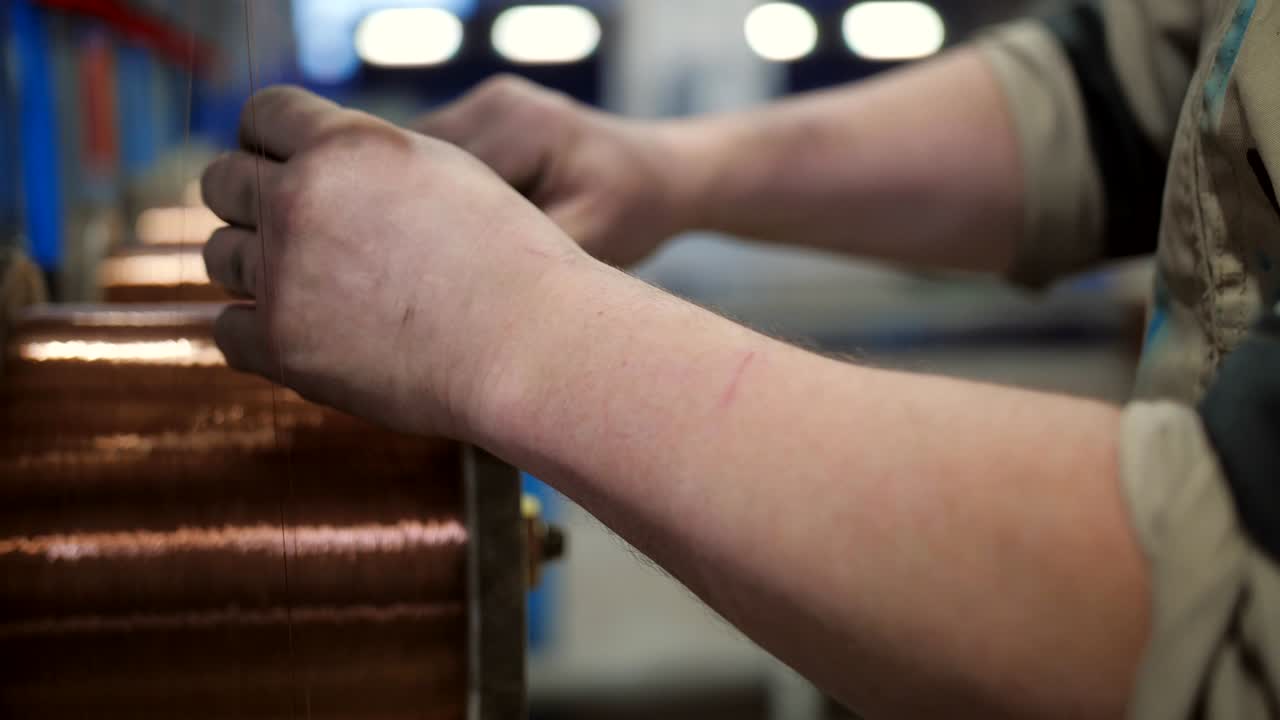 Mandlig arbejder på en kabelfabrik forbereder spole med kobbertråd til elkabel